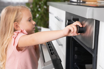 Little girl baking something in oven at home