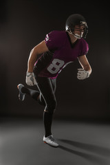 Fototapeta na wymiar American football player wearing uniform on dark background