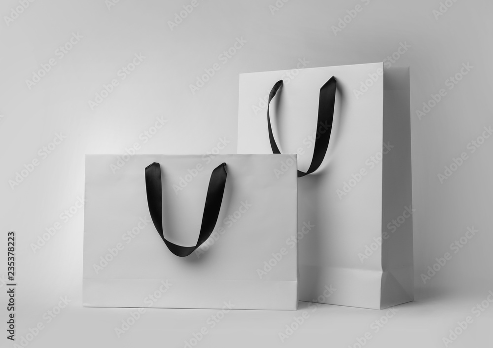 Wall mural Paper shopping bags with ribbon handles on white background. Mockup for design