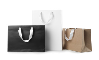 Paper shopping bags with ribbon handles on white background. Mockup for design