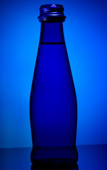 Blue glass bottle on a blue background against the light