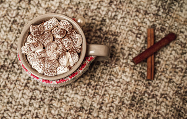 Cappuccino with marshmallows in a mug on a woolen scarf