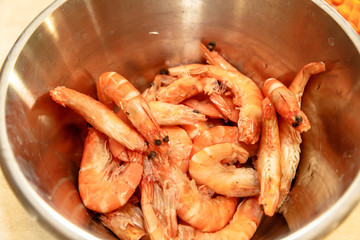 Orange shrimps lie in a metal bowl