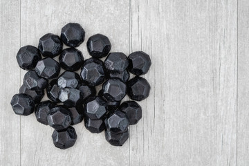 Pile of coal shaped candy on a gray washed wood background, as a naughty for Christmas concept