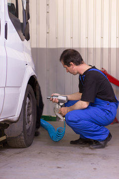 Mechanic is pumping up wheels in service station