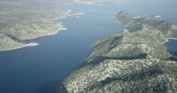 High aerial drone video panning left survey of landscape from Kekova Island, channel to Kalekoy Village and Simena Castle over Mediterranean Sea overview in Demre, Turkey. 4k at 23.97fps