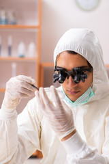 Naklejka premium Young biochemist wearing protective suit working in the lab