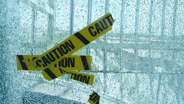 Broken window made of safety glass with caution stickers. Pickering, Canada. Handheld shot with stabilized camera.