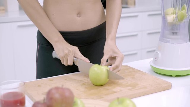 Sporty Asian woman prepare ingredient for make apple juice in the kitchen, female in sport clothing use organic fruit lots of nutrition making apple juice by herself at home. Healthy food concept.