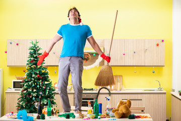 Young man cleaning kitchen after Christmas party 