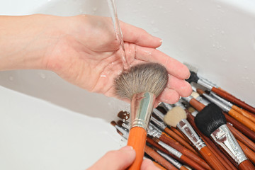 hands of makeup artist are washed brushes under running water