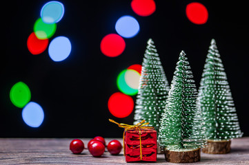 Fototapeta na wymiar Christmas gift boxes under pine tree on wooden table over bokeh background