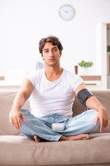 Young man measuring blood pressure at home