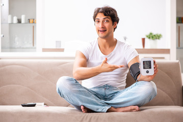 Young man measuring blood pressure at home