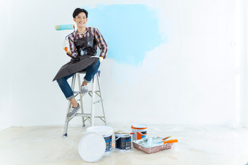 Asian man painting wall at home