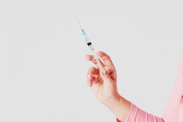 Disposable syringe in female hand on gray background isolated