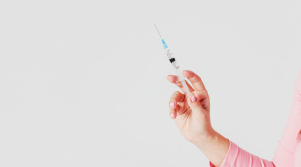 Disposable syringe in female hand on gray background isolated