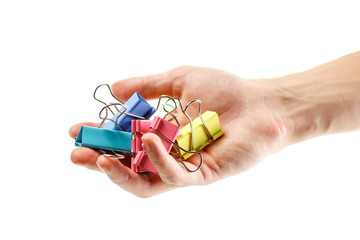 Hand holding stationery metal colored clips. Close up. Isolated on white background.