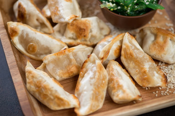 Pan fried japanese gyoza on a wooden serving tray, close-up, horizontal shot