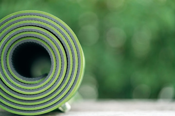 Fototapeta na wymiar close up of green yoga mat on the table, sport and healthy concept