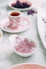Dessert with flowers and coffee on the table. Foodstyling with decor and sweets in purple.