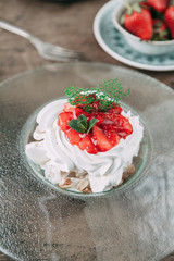 Pavlova dessert with berries in a beautiful composition. Foodstyling on a wooden background with coffee and strawberries.