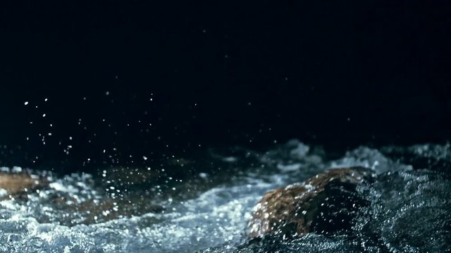 Slow motion of waves on dark water surface with play of flecks of bright light close up. Amazing dramatic natural background. Shooting with 180fps. Epic mystical and magic night view. Crystal clear