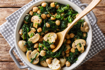Delicious braised chickpeas with spinach and mushrooms closeup in a bowl. horizontal top view