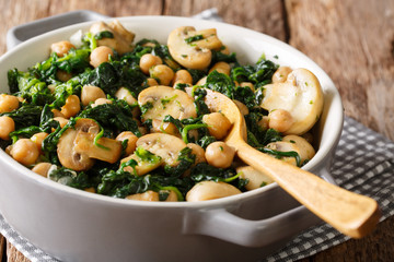 Healthy vegetarian food of chickpeas with spinach and mushrooms close-up in a bowl. horizontal