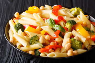 Italian penne pasta with chickpeas, vegetables, herbs and spices close-up in a plate. horizontal