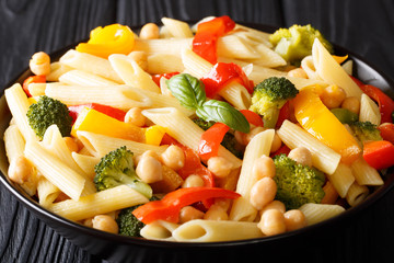 Penne pasta salad with chickpeas, broccoli, bell pepper and spices closeup in a plate. horizontal