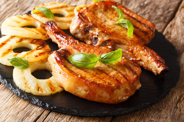 Freshly prepared delicious grilled pork chop in honey pineapple glaze close-up on slate. horizontal