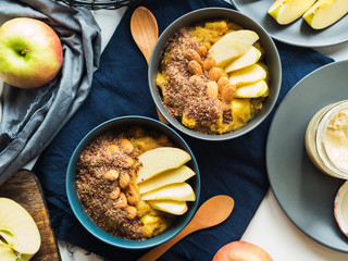 Cozy morning concept with turmeric amaranth porridge served with apples, flax seeds and almonds. Healthy plant based vegan breakfast. Flat lay