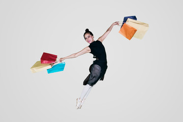 Beautiful ballerina is leaping with shopping bags
