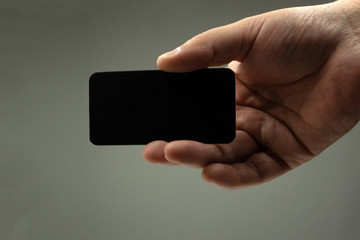 Man wearing blue jeans shirt and showing blank black business ca