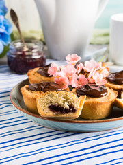 Cakes with frangipane, cherry jam and chocolate frosting. Romantic table setting with flowers. Mother's day card