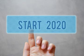 Finger pressing blue transparent patterned start 2020 button on virtual interface on gray...
