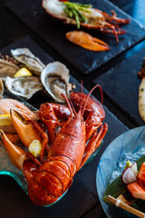 Boiled lobster, fresh oysters, shrimps, mussels and clams served in black stone plate.