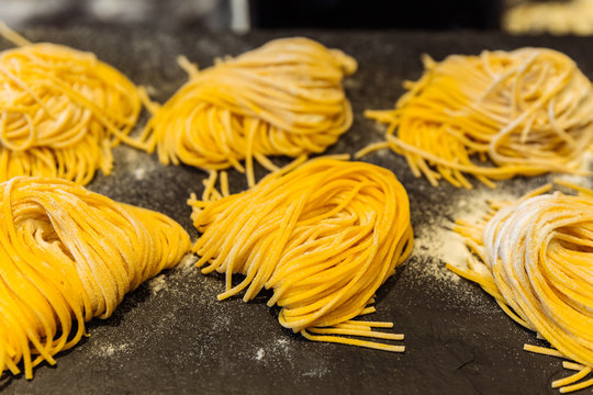Homemade piles of fresh egg spaghetti pasta that powdering flour to keep them from sticking.