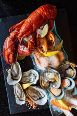 Crédence de cuisine en verre imprimé Crustacés Homard bouilli, huîtres fraîches, crevettes, moules et palourdes servis dans une assiette en pierre noire.
