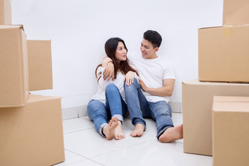 Romantic Asian couple sits with cardboard boxes