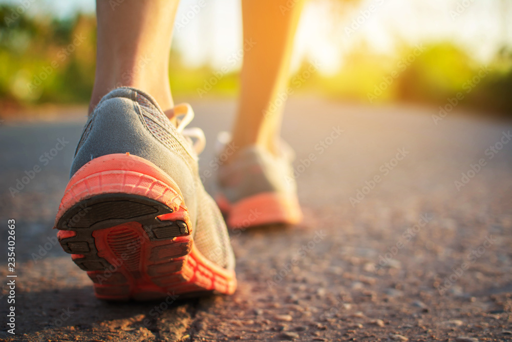 Wall mural feet of woman walking and exercise on the road during sunset.