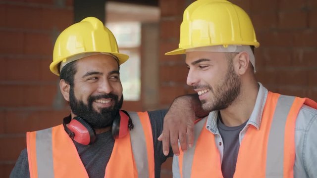 People working in construction site. Portrait of happy men at work in new house inside apartment building. Professional workers looking and smiling at camera as co-workers and friends. Slow motion