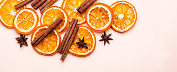 Christmas pink pastel background of Dry Oranges Slices and cinnamon sticks. Banner format
