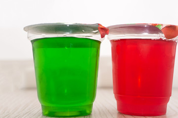 Sweet jelly with raspberries in glasses on table .