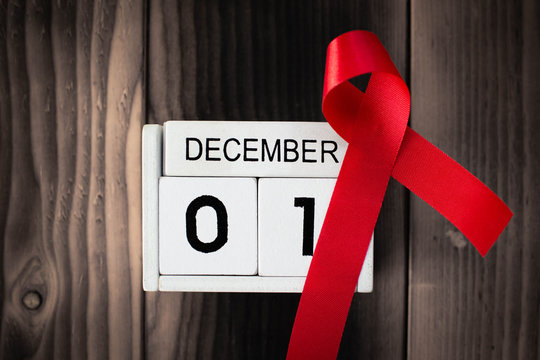 Red ribbon with calendar date 1 December on brown wood background, Concept World Aids Day.