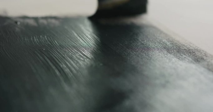Slow motion closeup painting plywood with brush with black paint