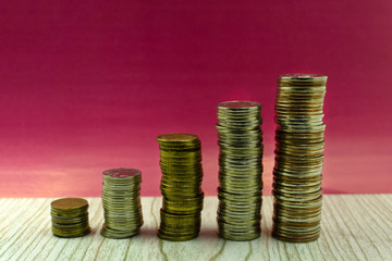Five stacks of coins with growth between stacking limits on white background.