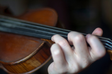 Violinist holds fingers on violin fingerboard