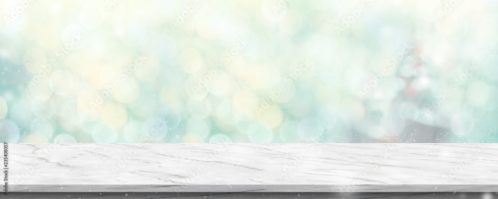 Aufkleber Empty white marble table with abstract blur green christmas tree and snow fall background with bokeh light.Mock up banner for display of product.